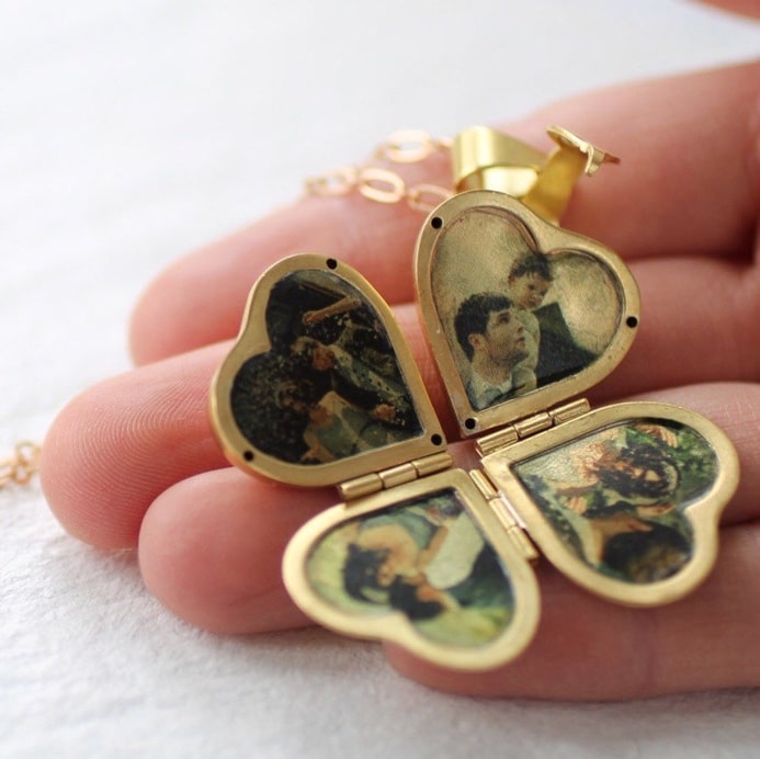 May include: A gold heart-shaped locket necklace with four compartments. Each compartment has a different photo inside. The locket is open and the photos are visible.