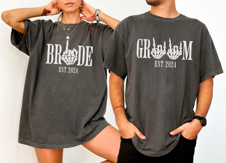 May include: Two gray t-shirts with white text and skeleton hand graphics. The text on the left shirt reads 'BRIDE EST 2024' and the text on the right shirt reads 'GROOM EST 2024'.