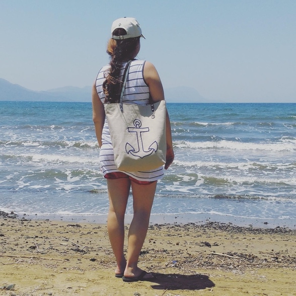 A beige canvas tote bag with a blue anchor embroidered on the front.