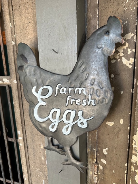 A metal sign with a chicken on it Description automatically generated