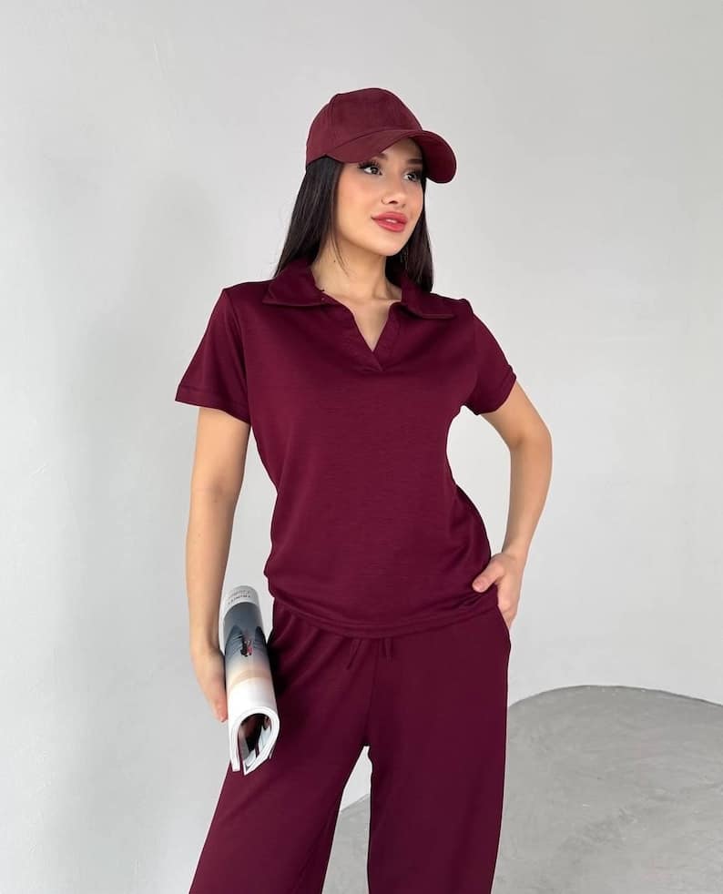 May include: A burgundy polo shirt with a V-neck collar and matching cap and pants. The short-sleeved shirt and pants are made of a soft material. The cap is a classic baseball style.