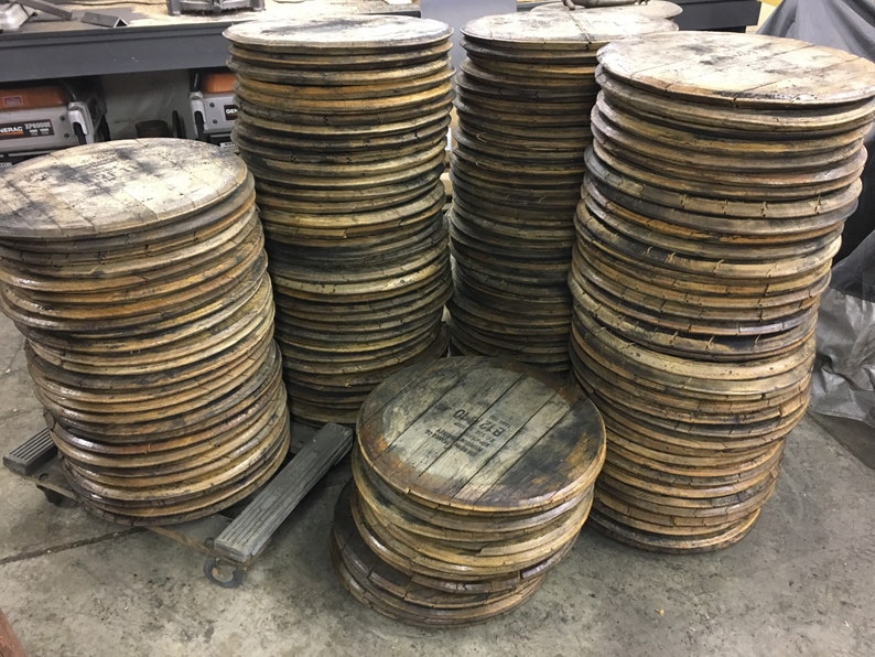 May include: A stack of wooden barrel heads, some with the text "Old 228" printed on them. The barrel heads are stacked in a warehouse setting.