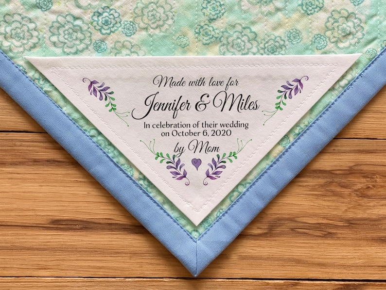 May include: A white triangular fabric label with a floral design and the text "Made with love for Jennifer & Miles In celebration of their wedding on October 6, 2020 by Mom".