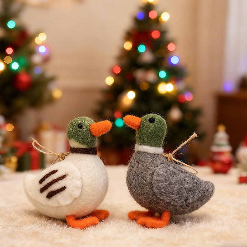 May include: Two felt duck ornaments with green heads, orange beaks and feet, and brown accents. One duck is white with brown wing details, the other is gray. Both have twine loops for hanging, perfect for Christmas tree decor.
