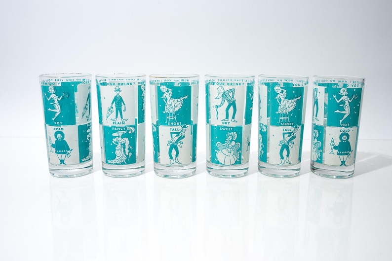 May include: Set of six vintage cocktail glasses with teal and white illustrations. Each glass features a different design, including figures and text such as "Hot Cold" and "Plain Fancy". The glasses are arranged in a row against a white background.