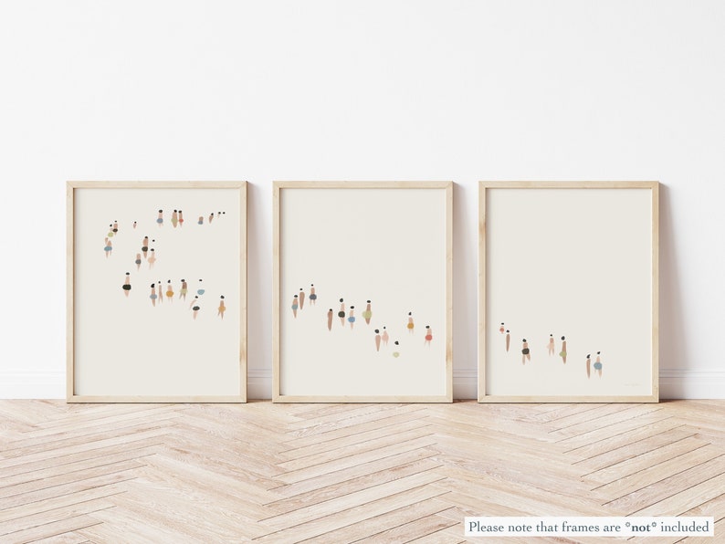 May include: Three framed prints with a minimalist design of people in various colors and sizes, arranged in a line on a light wood floor.