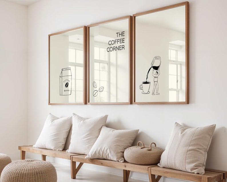May include: Three framed mirrors with wood-tone frames hang above a wooden bench with pillows. The mirrors feature black and white illustrations of coffee-related images, including a carton, beans, and a person pouring coffee into a cup. The text "THE COFFEE CORNER" is also displayed.